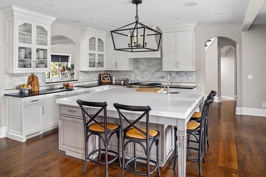 Modern kitchen with white marble countertops, dark cabinetry, and large stone island