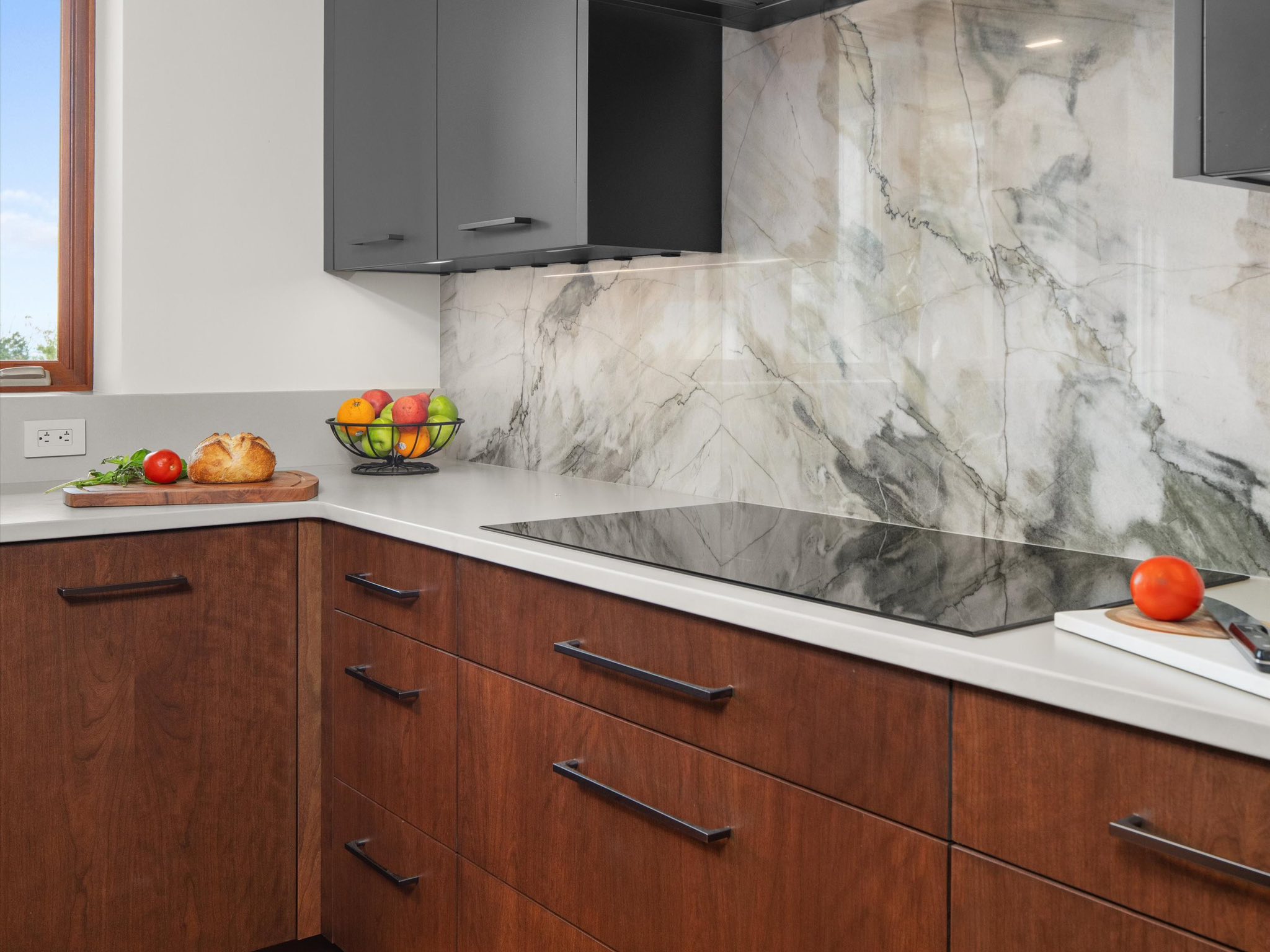Elegant kitchen featuring white marble countertops and backsplash with gold veining and white cabinetry